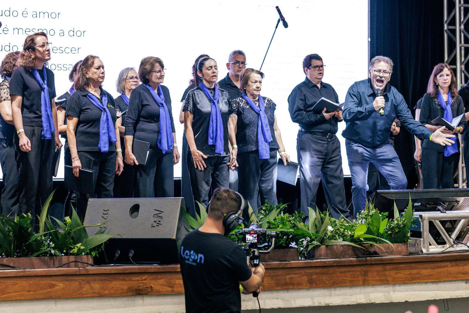 Cinegrafista filmando coral no palco